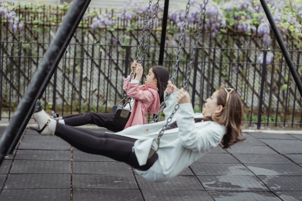 Asian mother and daughter spending quality time swinging in a playground.